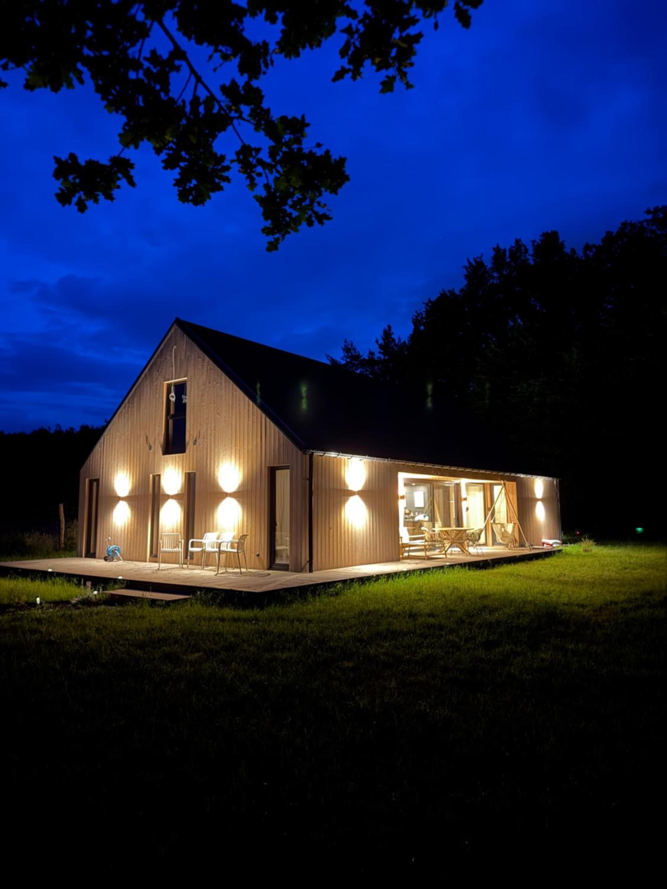 Drewniany dom nocą z jasno oświetlonymi oknami