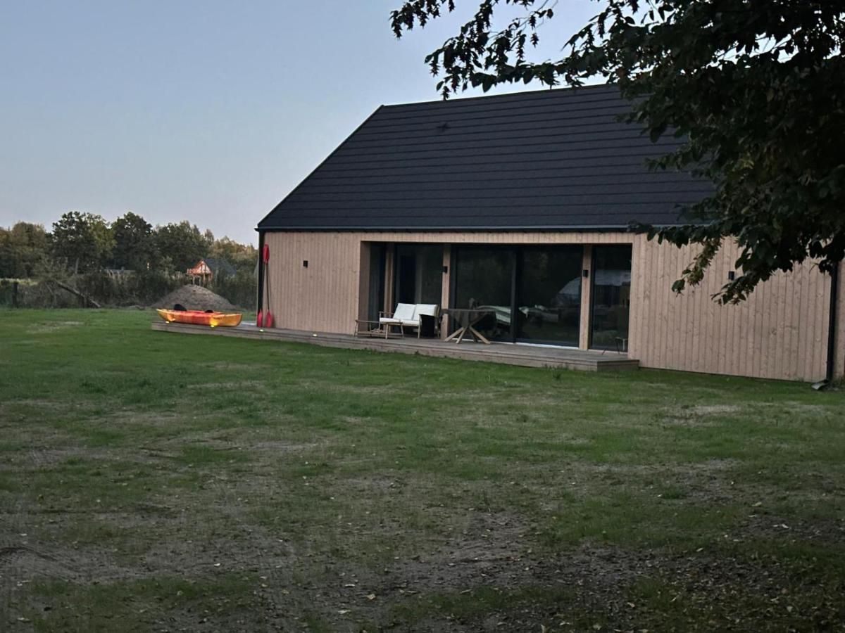 Dom z drewnianą elewacją, tarasem i trawnikiem